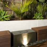 A close up view of the water feature. arecales, backyard, landscaping, outdoor structure, palm tree, plant, wall, brown