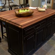 A solid mahogany countertop with black cabinetry of cabinetry, countertop, floor, flooring, furniture, hardwood, kitchen, table, tile, wood stain, black, brown