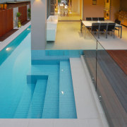 Pool runs alongside living room in contemporary home composite material, daylighting, floor, flooring, hardwood, leisure, leisure centre, property, real estate, swimming pool, tile, wood, wood flooring, gray, teal