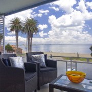 View of outdoor seating area overlooking a beach, apartment, balcony, home, house, interior design, property, real estate, sky, table, vacation, window, gray