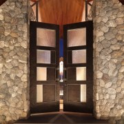 View of a large timber door leading to architecture, brick, light, light fixture, lighting, wall, window, wood, brown, black