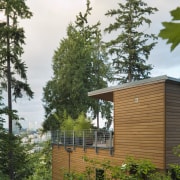 This three-level family home is perched on a architecture, cottage, facade, home, house, leaf, plant, real estate, shed, tree, wood, brown, white
