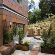 Exerior view of bathroom featuring sliding doors, pavers, backyard, courtyard, estate, home, house, landscape, landscaping, outdoor structure, property, real estate, yard, brown