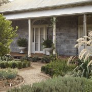 Exterior view of a colonial-styled architectural home with cottage, estate, garden, grass, home, house, landscape, landscaping, outdoor structure, plant, real estate, window, yard, brown