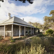 Exterior view of a colonial-styled architectural home with cottage, estate, farmhouse, home, house, landscape, plant, property, real estate, sky, tree, brown, white