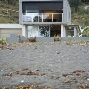 With a long, narrow design, this two-storey bach architecture, cottage, home, house, real estate, roof, water, gray