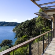 View of deck and side of house with cottage, estate, home, house, property, real estate, sky, tree, villa, water, teal