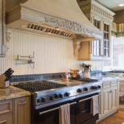 A custom-designed, French Provincial-style hood with a decorative cabinetry, countertop, cuisine classique, flooring, interior design, kitchen, brown, gray