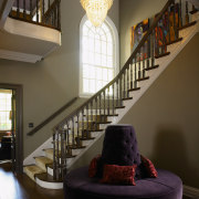 The centrally located stair hall is overlooked by architecture, ceiling, daylighting, estate, handrail, home, interior design, living room, lobby, room, stairs, wall, window, brown