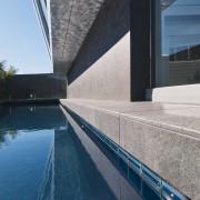 Image of a residential minimalist pool constructed by architecture, building, daylighting, reflection, sky, swimming pool, water, blue, gray