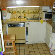 A view of the cramped and awkward original countertop, floor, flooring, kitchen, major appliance, property, room, brown, gray