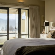 The master bedroom on the upper level has bed, bed frame, bedroom, home, hotel, interior design, real estate, room, suite, window, window covering, window treatment, wood, brown