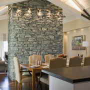 The central schist fireplace is left unadorned, as ceiling, dining room, interior design, living room, real estate, room, table, wall, gray, brown
