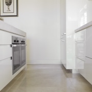 Image of kitchen area which features white cabinetry, floor, flooring, home, interior design, laminate flooring, property, real estate, room, tile, wall, wood flooring, gray