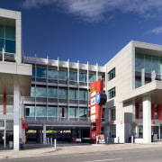 View of an office building featuring glazing which architecture, building, city, commercial building, corporate headquarters, facade, headquarters, metropolitan area, mixed use, real estate, sky, blue