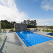 This new L-shaped pool, designed and built by estate, home, house, leisure, property, real estate, residential area, sky, swimming pool, villa, water, gray, teal