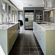 View of a kitchen which features a large cabinetry, countertop, cuisine classique, floor, home appliance, interior design, kitchen, gray