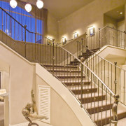 The grand staircase features wrought iron balustrades that baluster, ceiling, estate, handrail, home, interior design, real estate, stairs, orange, brown