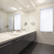 Bathrooms are designed in cool neutrals, with dark architecture, bathroom, ceiling, countertop, daylighting, floor, home, interior design, real estate, room, sink, tile, white