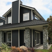 Image of the exterior of this home which building, cottage, elevation, facade, home, house, property, real estate, residential area, roof, siding, window, black