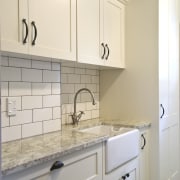 View of laundry, featuring a white butler's sink, bathroom accessory, bathroom cabinet, cabinetry, countertop, cuisine classique, floor, flooring, home, home appliance, kitchen, laundry room, room, sink, tile, wall, gray