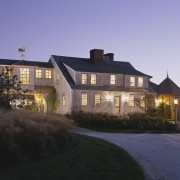 Exterior view of a large cottage with cedar building, cottage, estate, evening, facade, farmhouse, home, house, lighting, mansion, property, real estate, residential area, roof, sky, suburb, villa, window, black