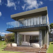 Exterior view of a holiday home with glass architecture, building, elevation, estate, facade, home, house, property, real estate, residential area, sky, villa, blue