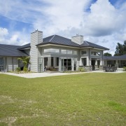 Image of this family home which creates a cottage, elevation, estate, facade, farmhouse, grass, home, house, land lot, landscape, lawn, mansion, property, real estate, residential area, roof, siding, sky, window, yard, brown, teal