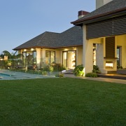 View of contemporary home with light-toned and beige backyard, estate, facade, hacienda, home, house, landscaping, lawn, leisure, mansion, property, real estate, residential area, resort, swimming pool, villa, window, green