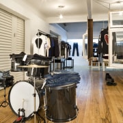 View of a drum kit which is used drum, drums, floor, flooring, hardwood, interior design, musical instrument, percussion, skin head percussion instrument, tom tom drum, wood flooring, white