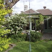 Exterior view of the villa's outdoor area prior backyard, cottage, courtyard, estate, garden, grass, home, house, landscaping, lawn, outdoor structure, plant, property, real estate, residential area, shrub, tree, yard, green, brown