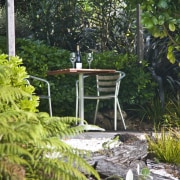 View of a landscaped garden with outdoor table backyard, botanical garden, flora, garden, grass, landscape, leaf, outdoor structure, plant, rainforest, shrub, tree, vegetation, walkway, woodland, yard, green