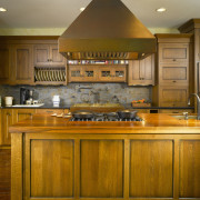 View of a kitchen which features an island cabinetry, countertop, cuisine classique, hardwood, interior design, kitchen, room, under cabinet lighting, brown, orange