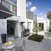 View of barbeque area featuring paving, plastered cladding, architecture, facade, home, house, property, real estate, residential area, window, gray
