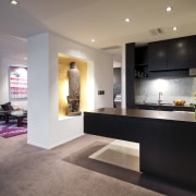 View of the kitchen where the island extends countertop, floor, flooring, interior design, kitchen, living room, lobby, room, gray, black