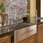 View of the kitchen which features a custom cabinetry, countertop, floor, flooring, hardwood, home, interior design, kitchen, room, sink, tile, wall, brown