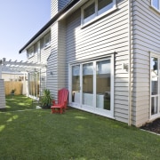 Exterior view of a new home designed by backyard, cottage, facade, grass, home, house, lawn, porch, property, real estate, residential area, siding, window, yard, white