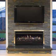 View of living area which features the Eastside fireplace, hearth, heat, black