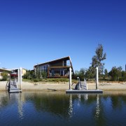 Exterior view of a canal-side beach house which cottage, home, house, leisure, real estate, reflection, sky, water, waterway, blue