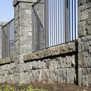 View of the stone wall with metal sections building, facade, fence, outdoor structure, stone wall, structure, wall, window, gray