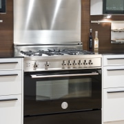 View of a contemporary kitchen which features a cabinetry, countertop, cuisine classique, furniture, gas stove, home appliance, kitchen, kitchen appliance, kitchen stove, major appliance, oven, small appliance, white, black