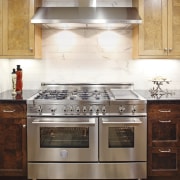 View of a contemporary kitchen which features a cabinetry, countertop, cuisine classique, floor, flooring, furniture, gas stove, hardwood, home appliance, interior design, kitchen, kitchen appliance, kitchen stove, major appliance, oven, room, tile, under cabinet lighting, wood flooring, white, brown