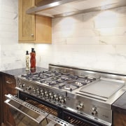 View of a contemporary kitchen which features a countertop, floor, flooring, kitchen, kitchen appliance, white