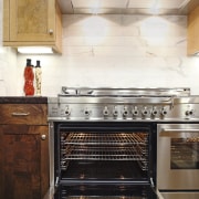 View of a contemporary kitchen which features a cabinetry, countertop, floor, flooring, home appliance, interior design, kitchen, kitchen appliance, kitchen stove, oven, tile, white, brown