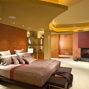 View of the master suite, bed, fireplace, recessed architecture, bed frame, bed sheet, bedroom, ceiling, floor, flooring, home, hotel, interior design, lighting, living room, room, suite, wall, wood, brown, orange