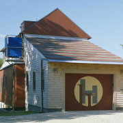 Exterior view of this home which features an building, facade, home, house, real estate, roof, shed, teal