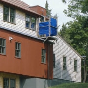 Exterior view of this home which features an building, cottage, elevation, facade, home, house, property, real estate, residential area, roof, siding, window, gray
