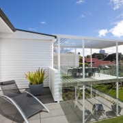 The renovated house features an elevated deck on home, house, outdoor structure, patio, property, real estate, white