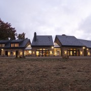 Low stucco walls enclose this new country house, cottage, estate, farmhouse, home, house, landscape, property, real estate, roof, siding, sky, white, black