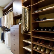 View of walk-in closet featuring shelving and storage. cabinetry, closet, furniture, room, wardrobe, black, brown